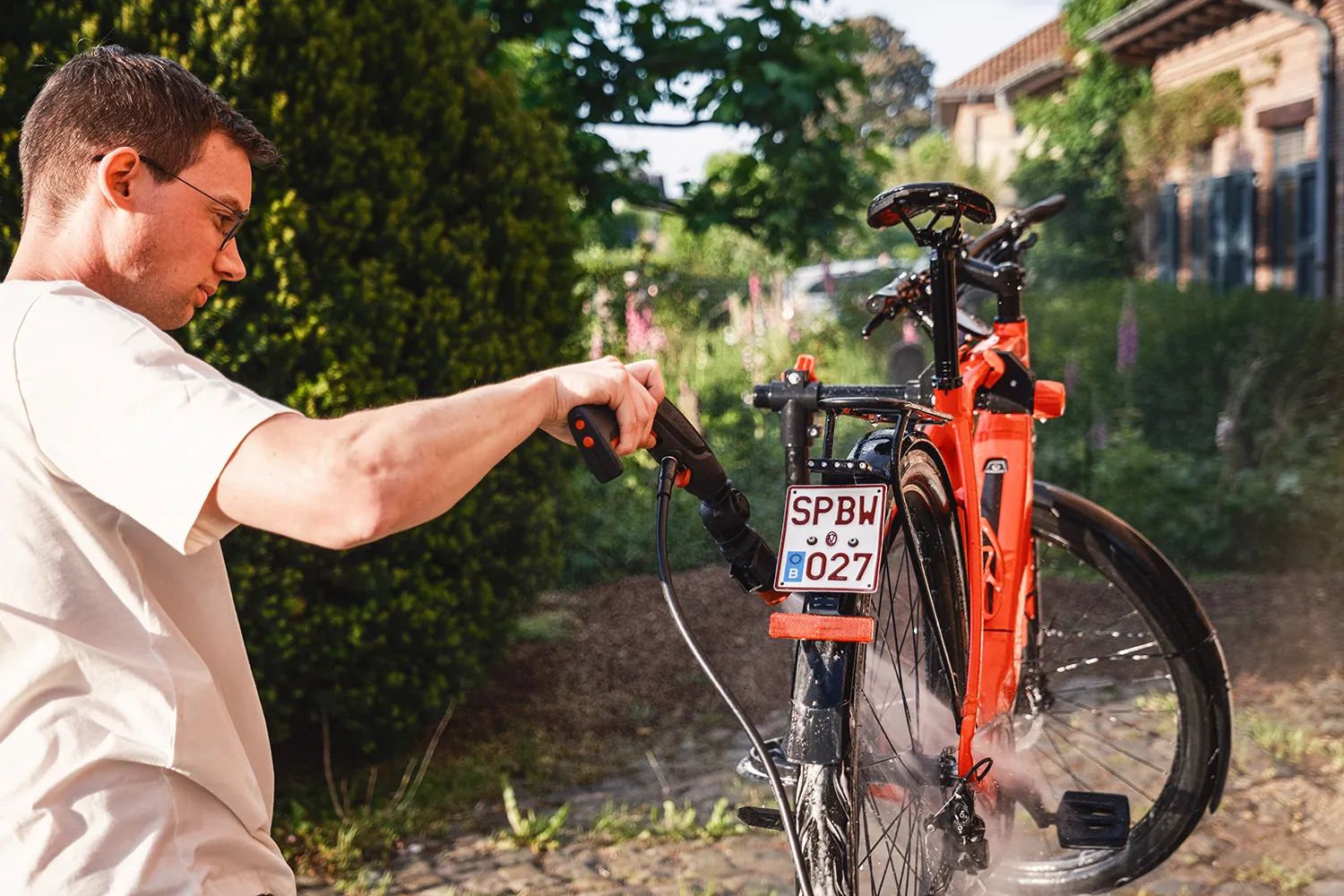 Background image, man holding a water gun cleaning a red bike